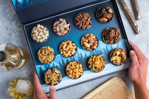 Gourmet nuts advent calendar with 12 tins featuring salted pistachios, Cajun cashews, and more, perfect for Christmas gifting.