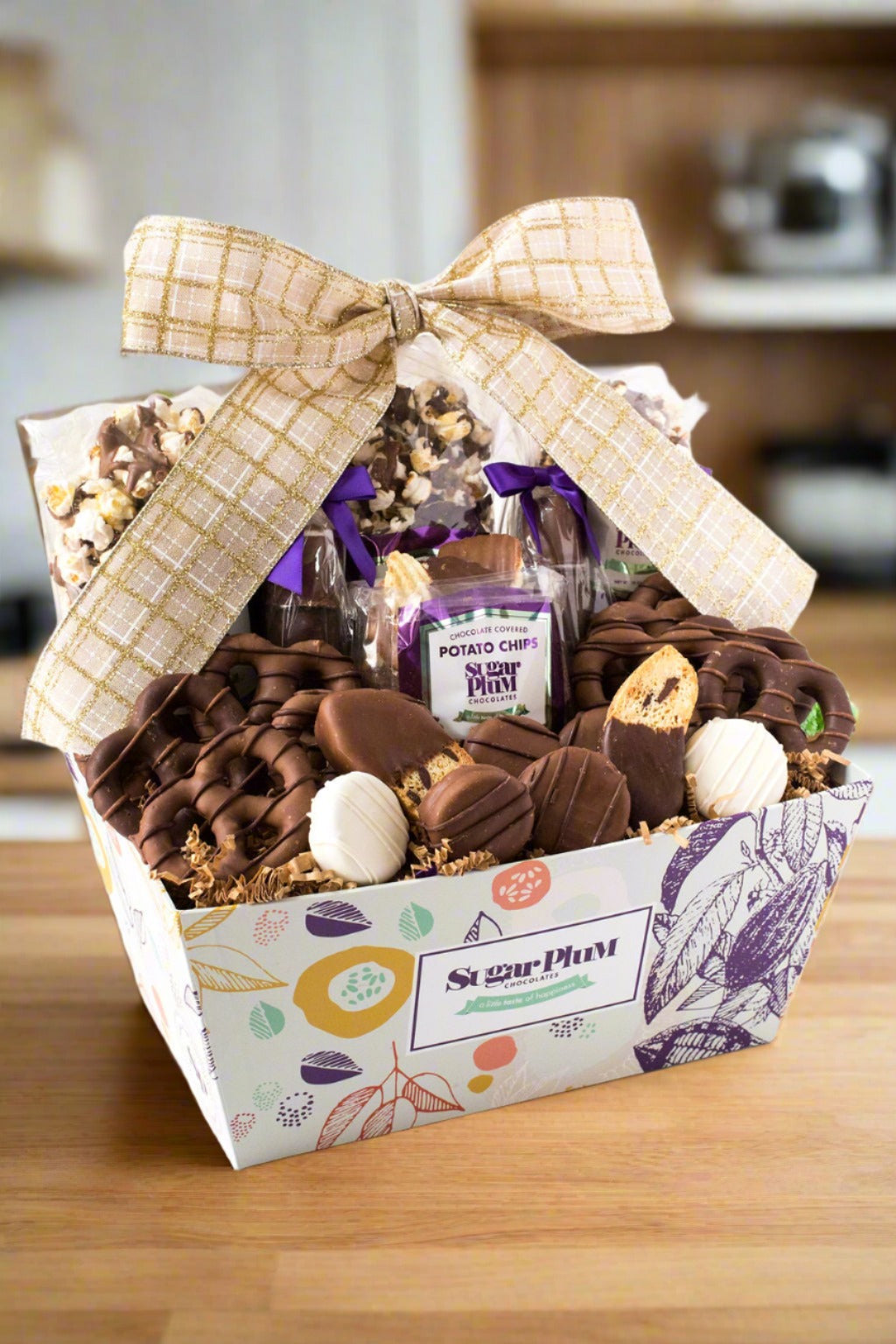 Gift basket with a variety of snacks and a large bow on a wooden surface.