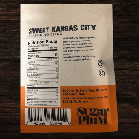 Sweet Kansas City BBQ seasoning blend package with nutrition facts and ingredients by Sugar Plum on a wooden surface.