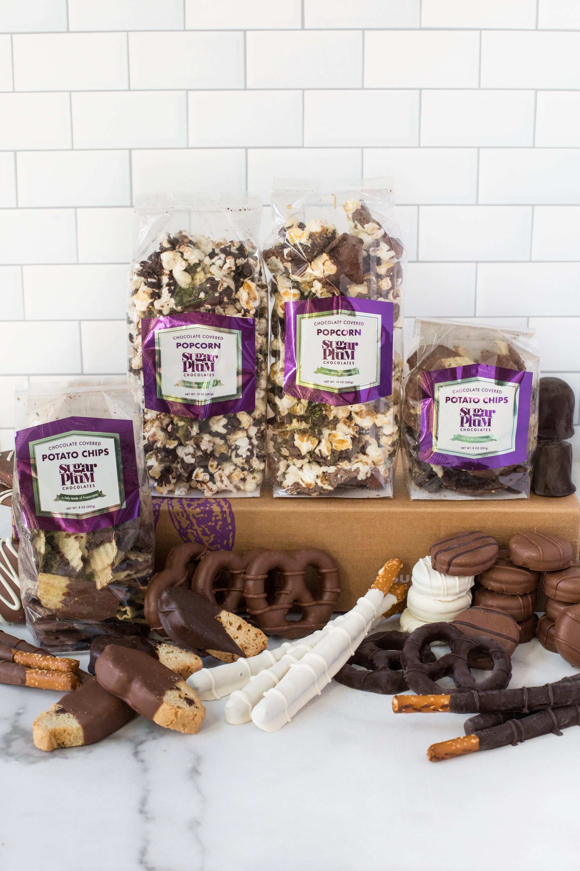 Gourmet chocolate assortment with pretzels and popcorn, featuring dark, milk, and white chocolate snacks in Sugar Plum's gift box.