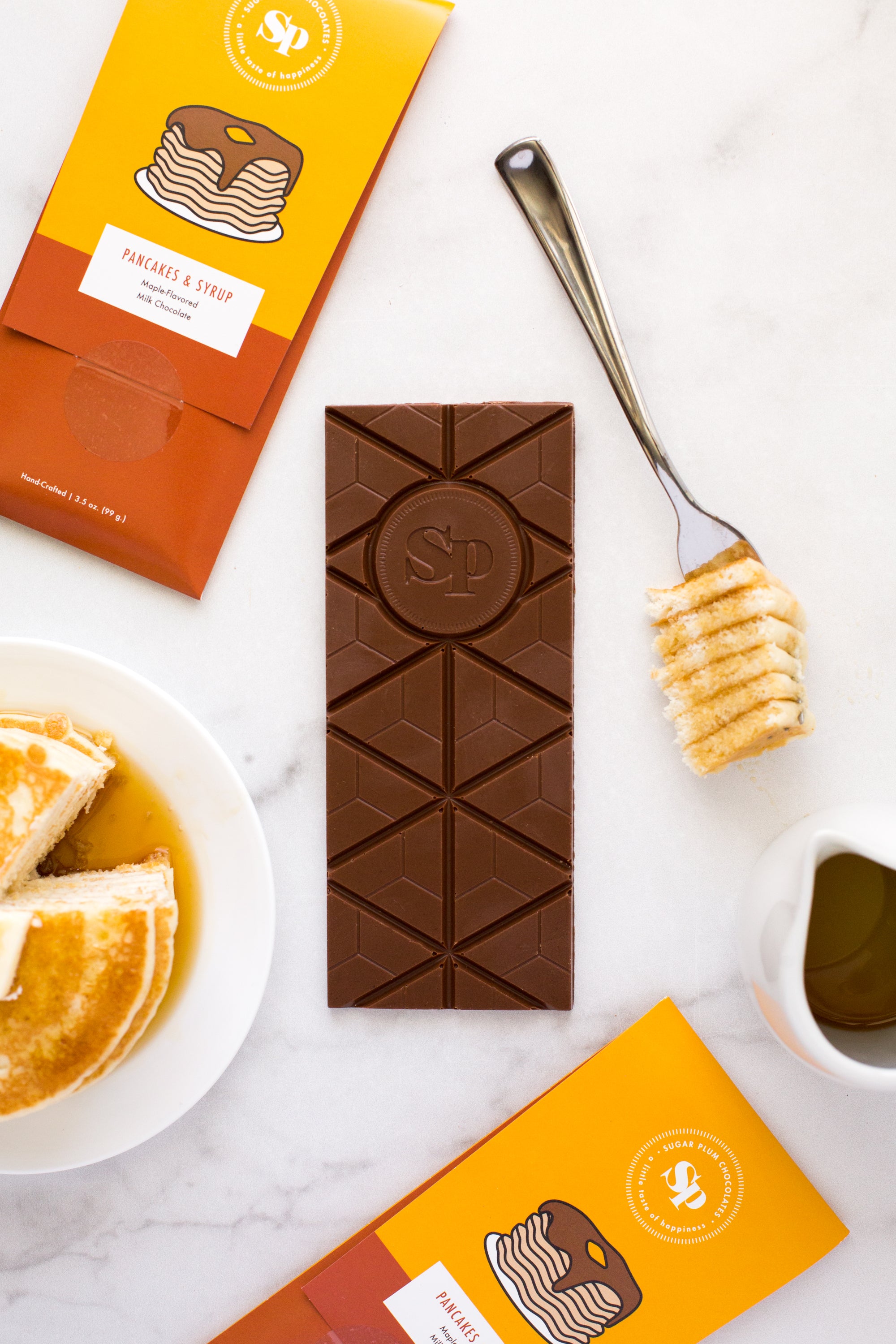 Nostalgic Chocolate Bar with Pancakes & Syrup flavor, surrounded by pancake stacks and syrup, from Sugar Plum's handcrafted collection.