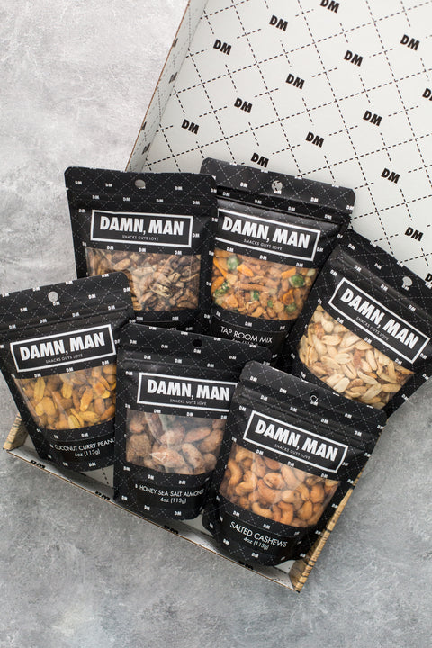 Manly Nut Box with six assorted bags of gourmet kettle-cooked nuts in a black and white gift box.