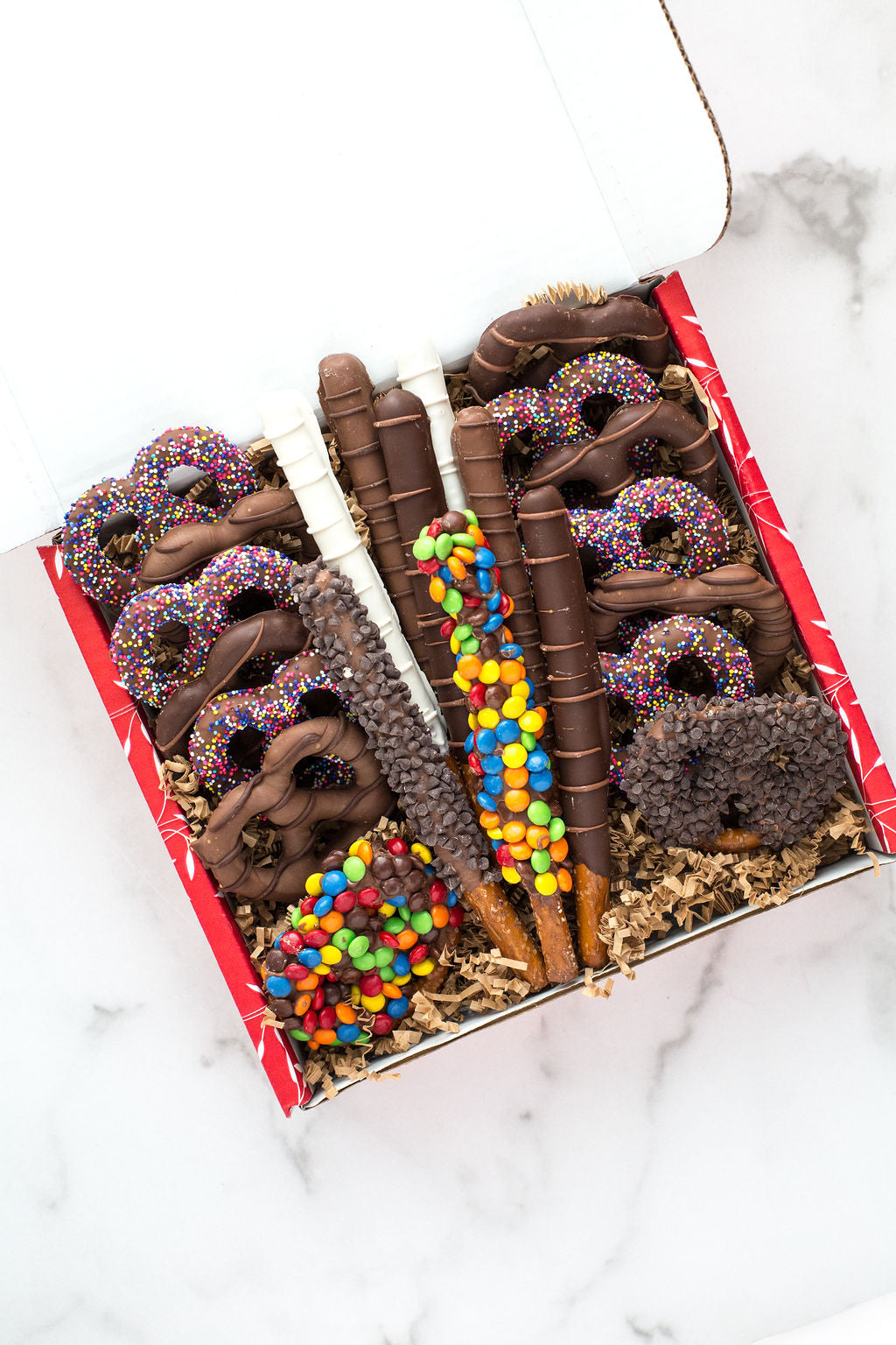 Assorted chocolate-covered pretzel gift box with colorful toppings, perfect for gifting and holiday treats.