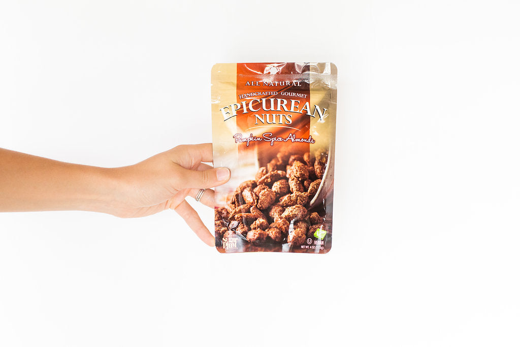 Hand holding a bag of Epicurean Nuts Pumpkin Spice Almonds with all-natural ingredients.