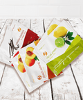 Assorted tea packets including citrus green, peach oolong, and vanilla rooibos on a rustic wooden surface.