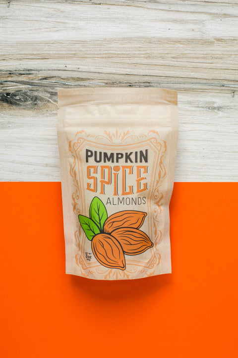 "Kettle-Cooked Pumpkin Spice Almonds in festive packaging on an orange background"