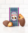 Milk chocolate covered biscotti in festive box, featuring delicious holiday treats on a white tiled background.