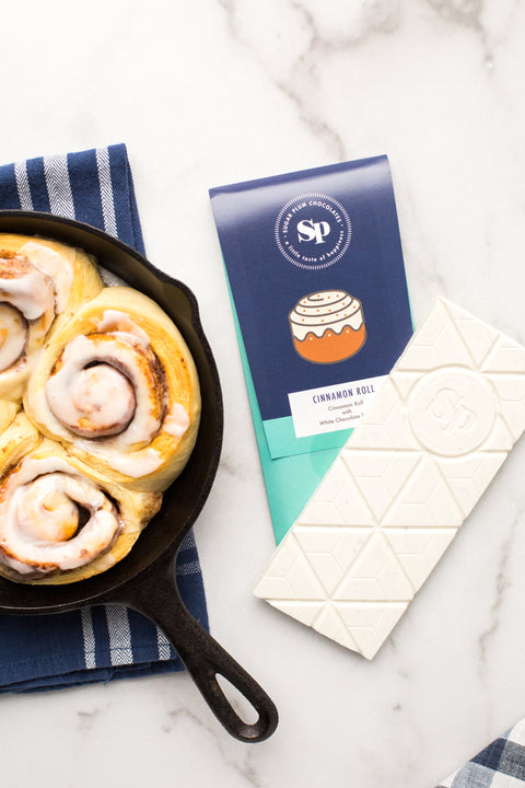 Cinnamon Roll White Chocolate Bar with skillet cinnamon rolls on marble background.