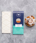 Cinnamon Roll White Chocolate Bar with Cinnamon Roll and Packaging on Gray Background