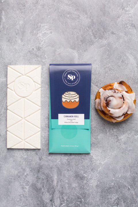 Cinnamon Roll White Chocolate Bar with Cinnamon Roll and Packaging on Gray Background