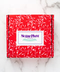 Red Sugar Plum Chocolates gift box with white leaf pattern, ideal for gourmet chocolate assortment gifts.