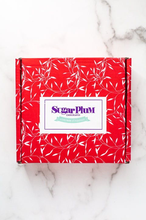 Red Sugar Plum Chocolates gift box with white leaf pattern, ideal for gourmet chocolate assortment gifts.