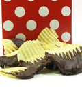Chocolate-covered potato chips in front of a red polka dot bag, showcasing a sweet and salty snack.