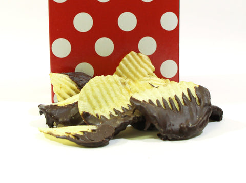 Chocolate-covered potato chips in front of a red polka dot bag, showcasing a sweet and salty snack.
