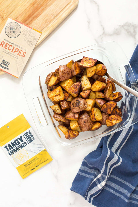 Roasted potatoes seasoned with Tangy Memphis spice mix from BBQ Blends, served in a glass dish on a white countertop.