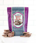 Milk Chocolate Holiday Spiced Cookie Bark with festive packaging and sprinkled chocolate pieces on a white countertop.