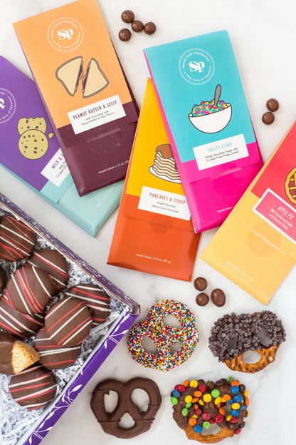 Nostalgic Chocolate Bar Gift Box with assorted flavors and sweet treats, featuring colorful packaging and chocolate-coated pretzels.