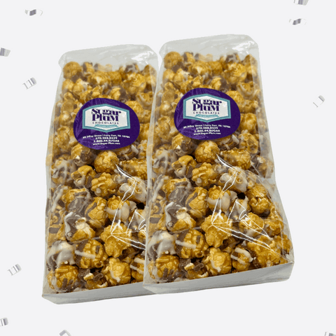 Two bags of Sugar Plum caramel corn with white and milk chocolate drizzle, packaged elegantly for gifting.