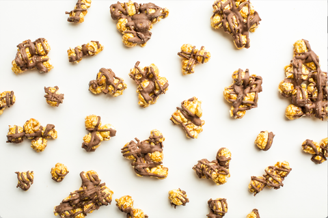 Pumpkin spice popcorn drizzled with milk chocolate on a white background, showcasing a tasty autumn gourmet snack.