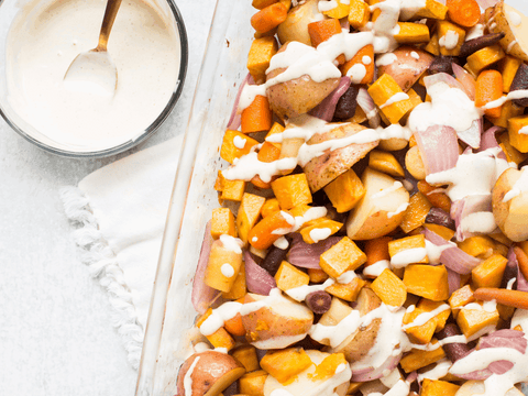 Roasted vegetables with creamy sauce featuring potatoes, carrots, and onions in a baking dish, perfect for a zesty horseradish seasoning.
