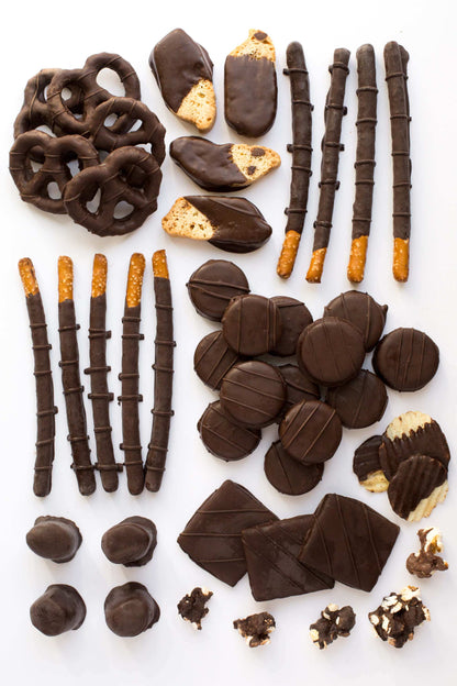 Gourmet assortment of handcrafted dark chocolate-covered snacks from Sugar Plum's gift box, featuring pretzels, cookies, and more.