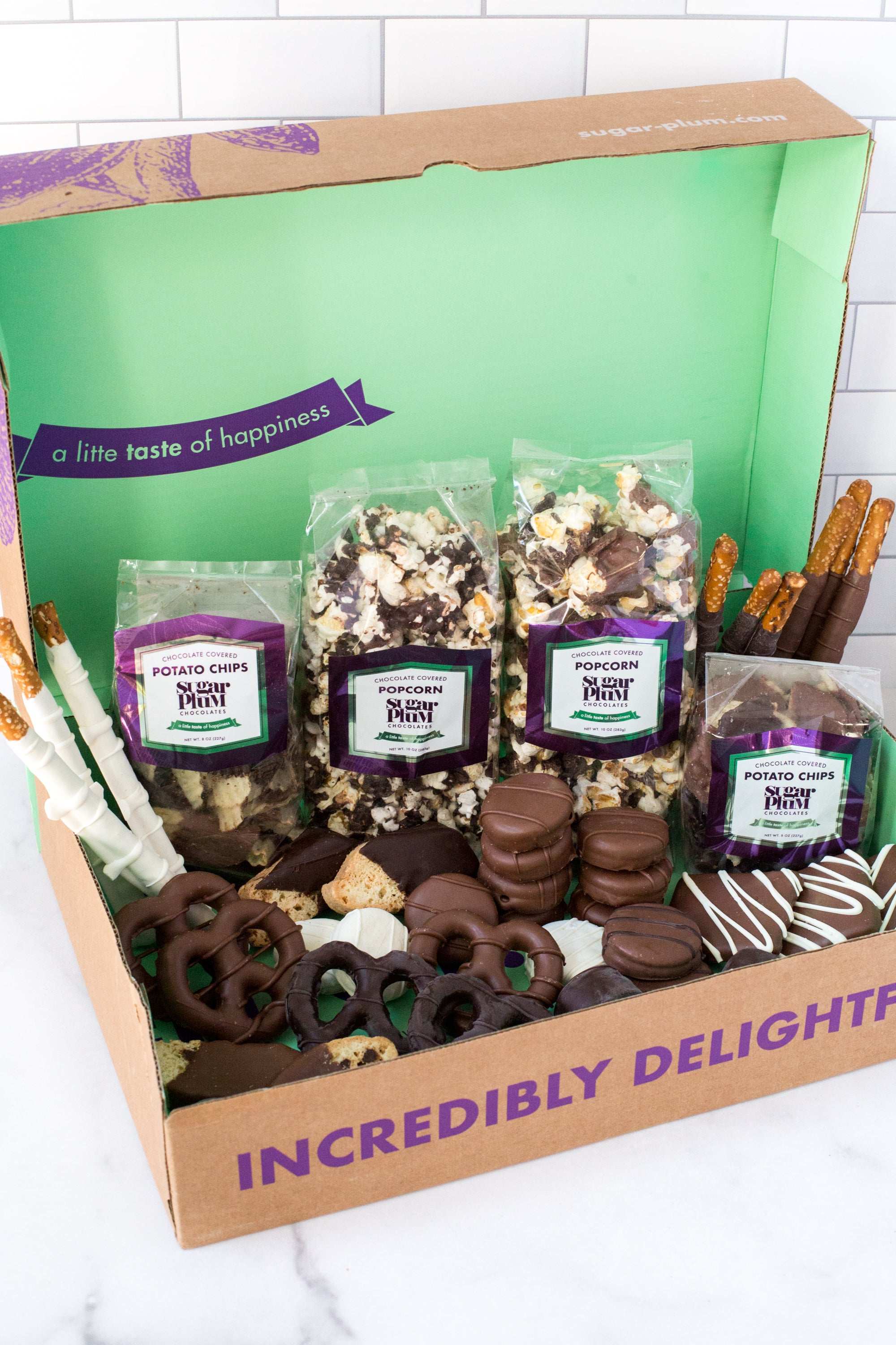 Gourmet chocolate assortment gift box with popcorn, chocolate-covered pretzels, and snacks in milk, dark, and white chocolate.