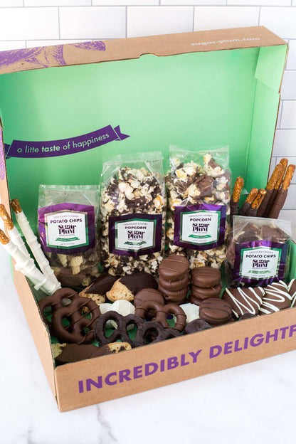 Gourmet chocolate assortment gift box with popcorn, chocolate-covered pretzels, and snacks in milk, dark, and white chocolate.