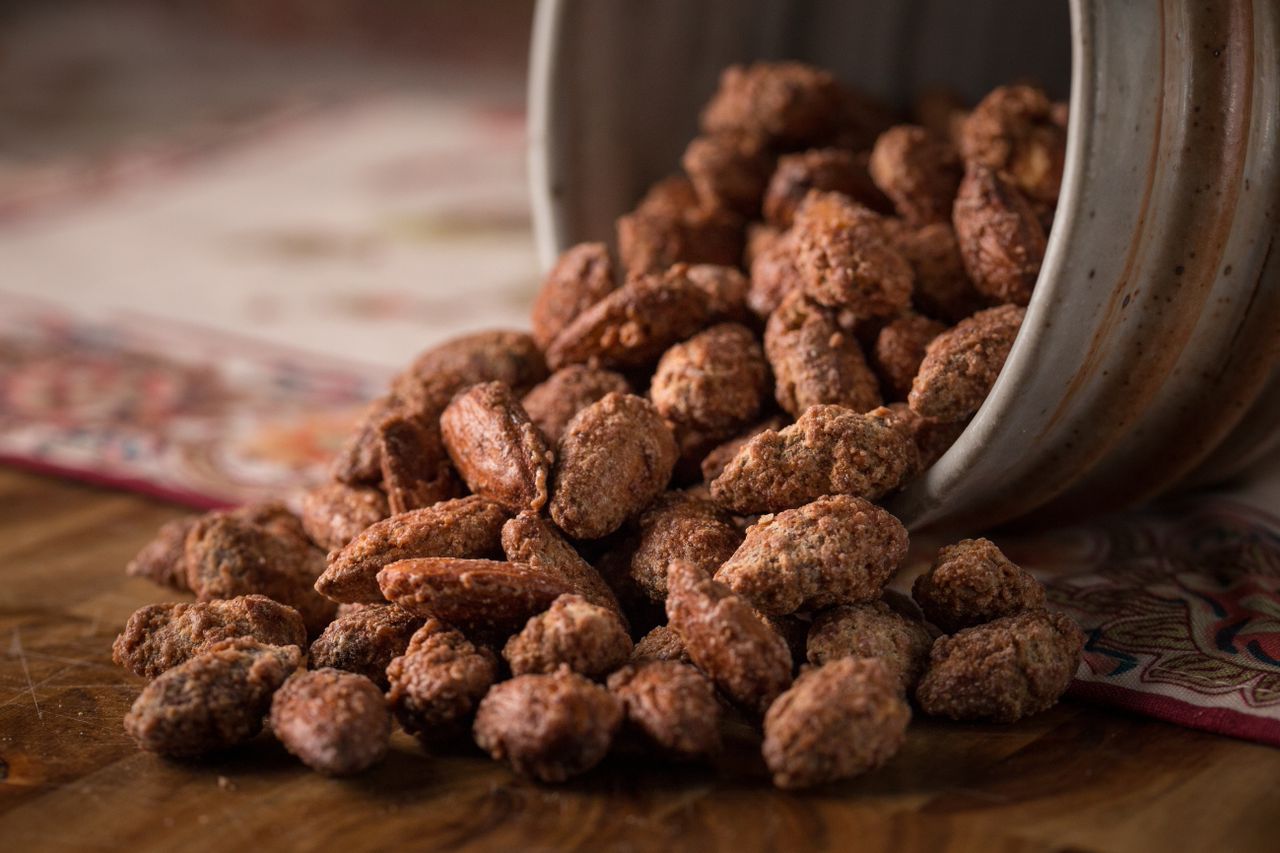 Gourmet cherry-flavored almonds spilling from a jar, showcasing Sugar Plum's Epicurean Nuts, perfect for snacking and dishes.