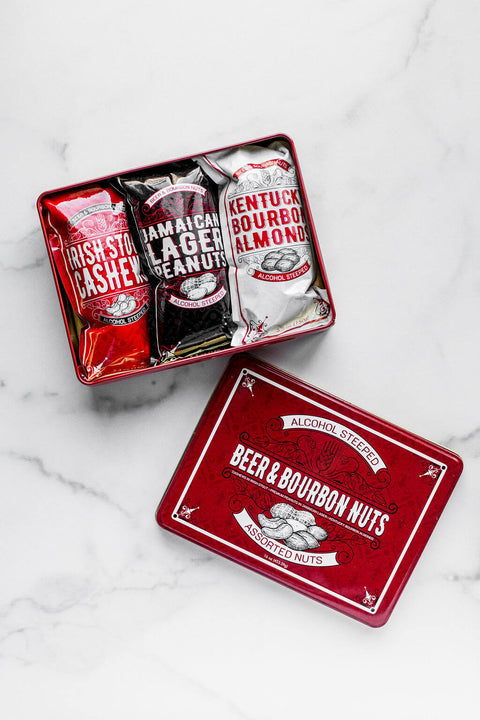 Beer & Bourbon Liquor Nuts Gift Tin with Irish Stout Cashews, Jamaican Lager Peanuts, Kentucky Bourbon Almonds on marble background.