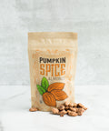 Bag of pumpkin spice almonds with scattered nuts, showcasing vegan, dairy-free fall snack featuring cinnamon, nutmeg, and ginger.