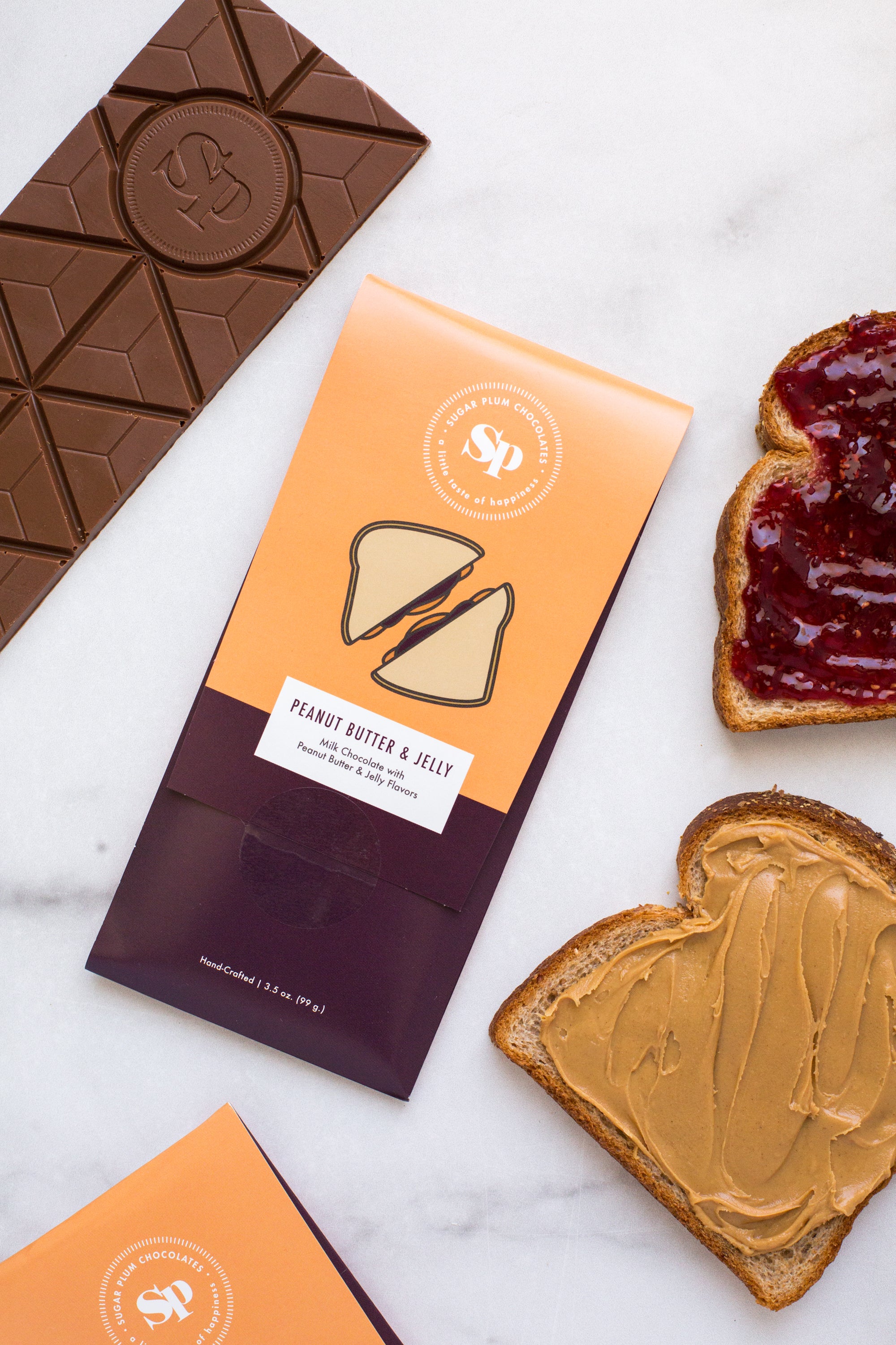 Nostalgic Peanut Butter & Jelly Chocolate Bar with bread slices topped with peanut butter and jelly, displayed on a marble surface.