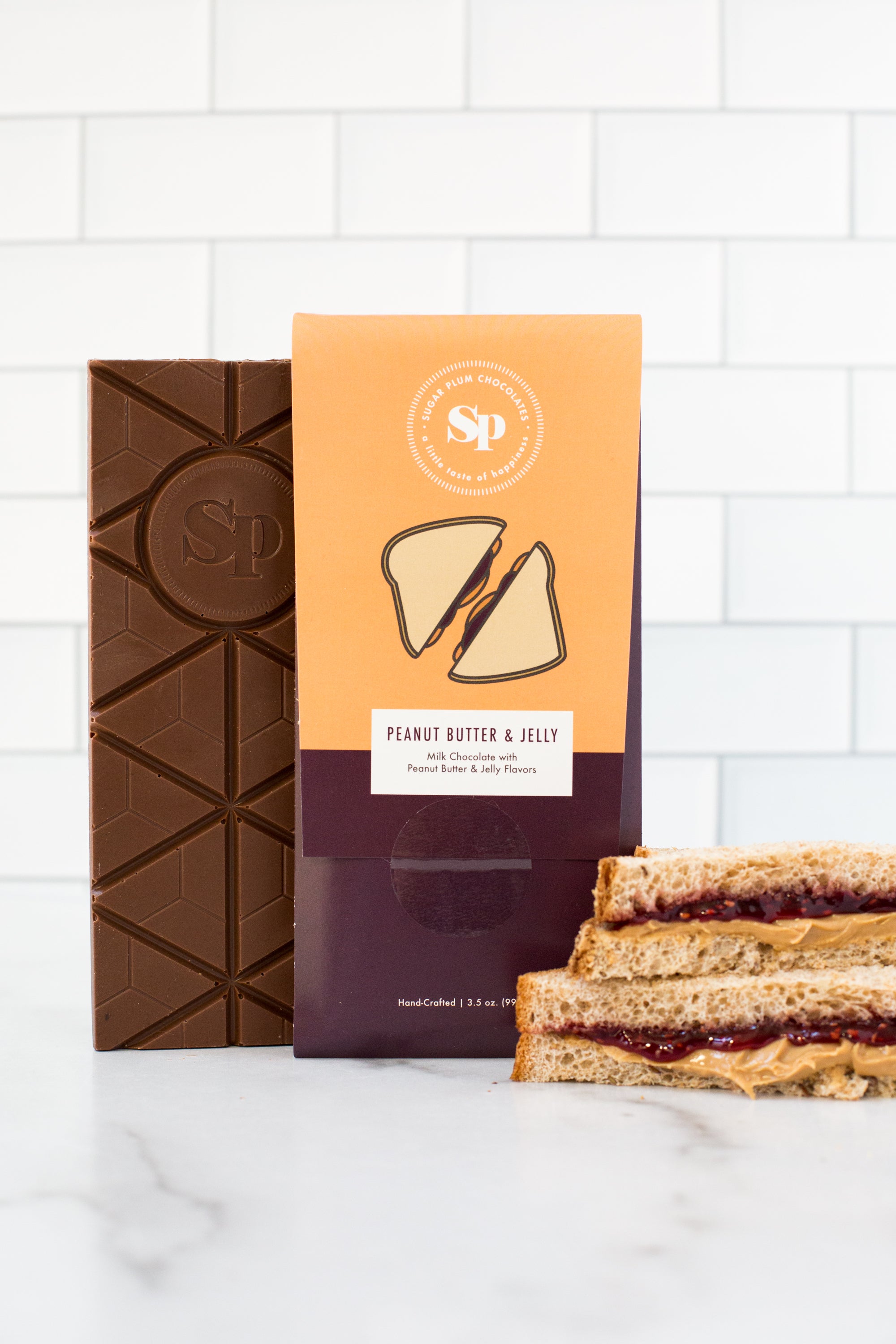 Nostalgic Peanut Butter & Jelly Chocolate Bar with peanut butter and jelly sandwich on a white background.