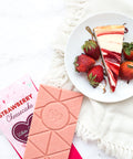 Strawberry Cheesecake White Chocolate Bar with Fresh Strawberries and Slice of Cheesecake on a Plate