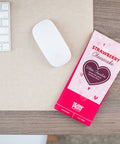 Strawberry Cheesecake White Chocolate Bar on a Desk Next to a Keyboard and Mouse
