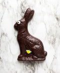 Handmade Dark Chocolate Easter Bunny with spring flower detail and eye on marble background.