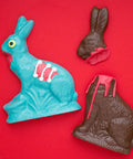 Handcrafted chocolate zombie bunny and victim set, limited edition Halloween or Easter candy gift, on a red background.