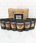 Manly Nut Box with six bags of assorted hand-crafted nuts arranged in front of a rustic gift box.