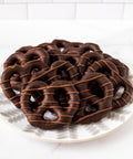 Chocolate-covered pretzels on a decorative plate, drizzled with chocolate, perfect for gifting or snacking.