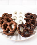 Assorted handcrafted chocolate-covered pretzels on a plate, featuring milk, dark, and white chocolate, perfect for snacking and gifting.