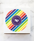 White box type with a rainbow color circle in the center.