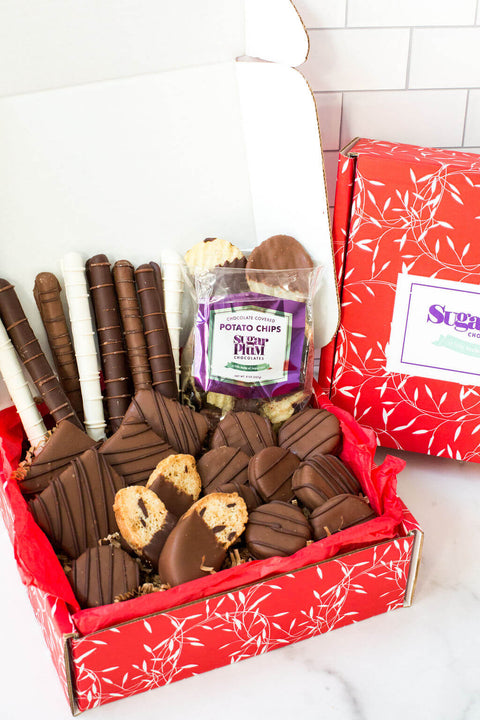 Gourmet chocolate gift box with assorted hand-dipped treats including chocolate-covered potato chips, cookies, and pretzels.