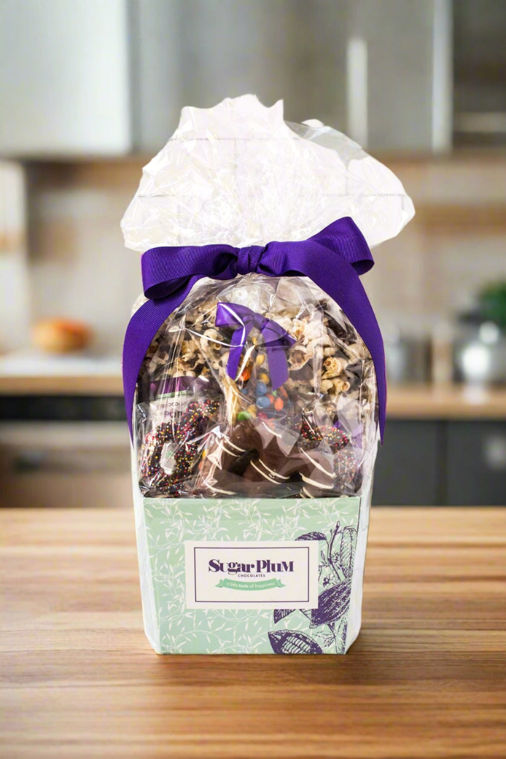 Gourmet chocolate gift basket by Sugar Plum, decorated with a purple ribbon, featuring handcrafted chocolate-covered treats.