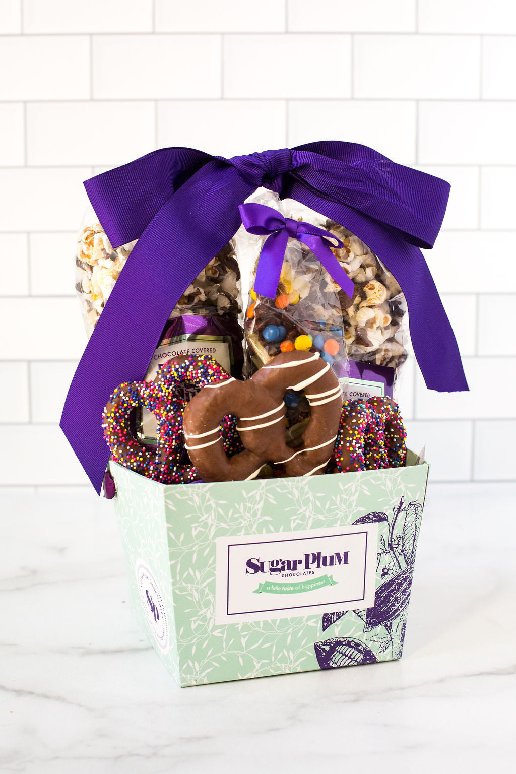 Sugar Plum's Perfect Size Gourmet Chocolate Gift Assortment includes a mouth-watering variety of chocolate-covered delectables and includes an assortment of chocolate-dipped potato chips covered with candied chocolate gems, chocolate-dunked pretzels and our famous chocolate-drizzled popcorn.