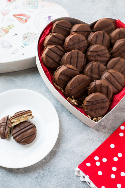 Heart-shaped box with milk chocolate-covered peanut butter cracker cookies and a red polka dot napkin.