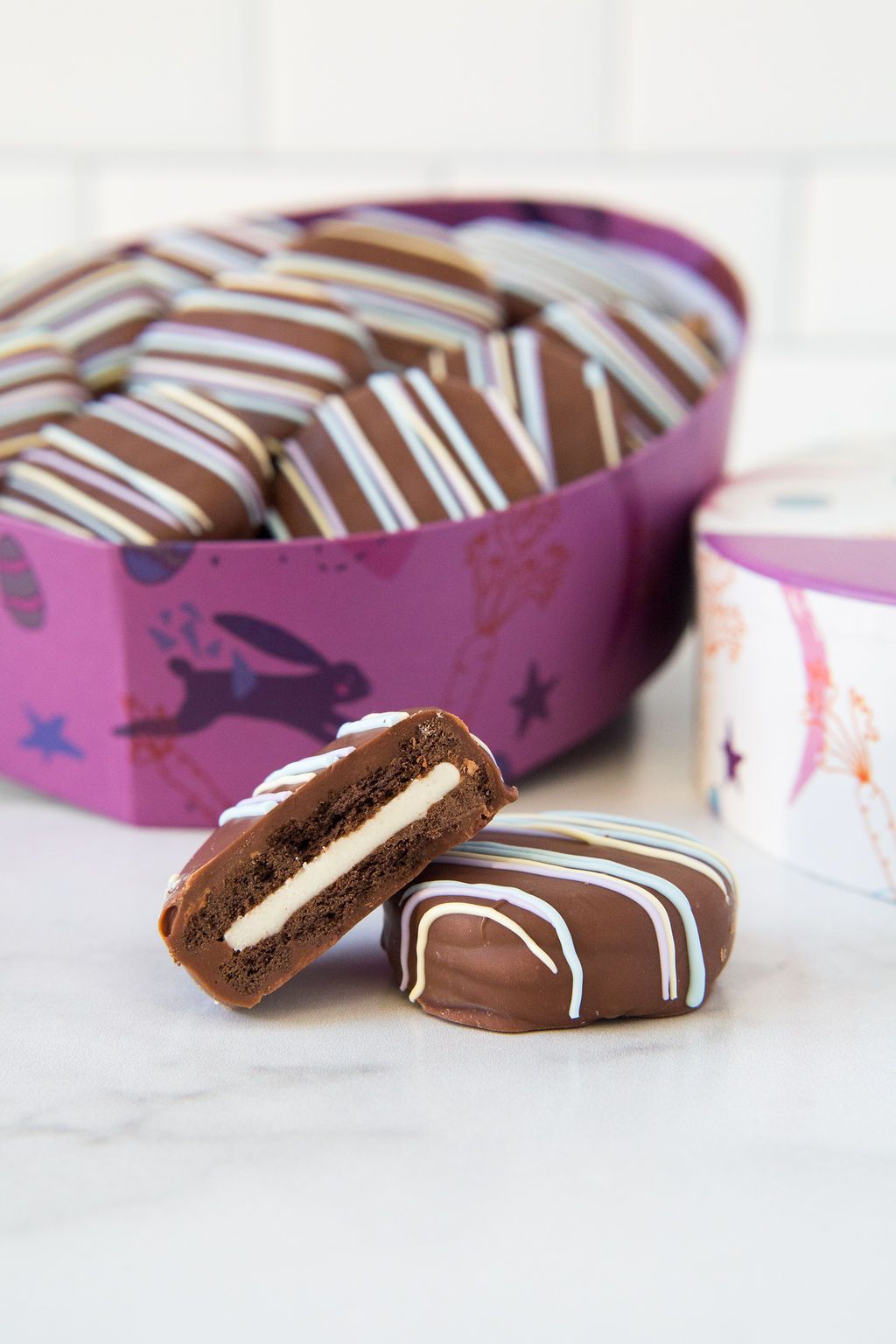 Egg-shaped stainless box in the background and a milk chocolate sandwich cookies.