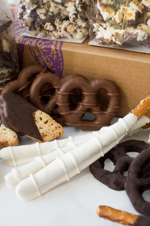 The image shows chocolate-coated pretzel, rough dough snacks, and sticks together with the popcorn.