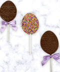 Easter Egg Nonpareil Lollipops with purple bows on marble background