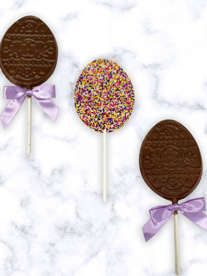 Easter Egg Nonpareil Lollipops with purple bows on marble background