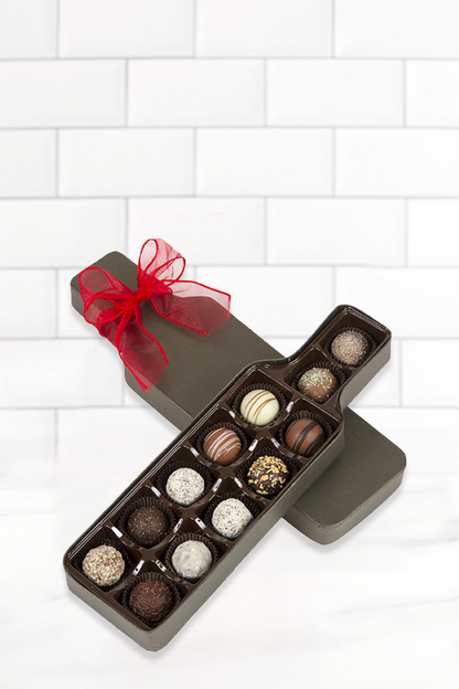 Wine truffle box assortment with 12 handcrafted chocolate truffles in a wine bottle-shaped box, adorned with a red ribbon.
