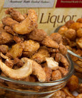 Assorted gourmet nuts with Irish Stout Cashews, Jamaican Lager Peanuts, and Bourbon Almonds in glass bowls from gift tin.